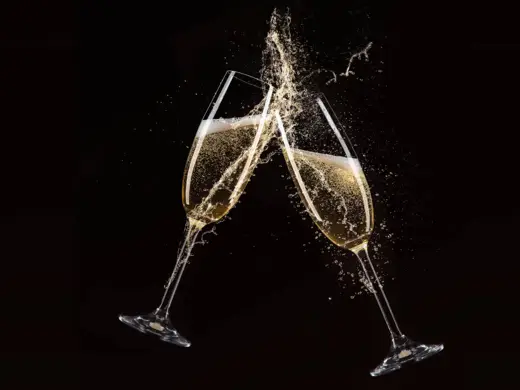 Black & Gold Silvestergala 2025 Zwei Sektgläser stoßen aneinander vor einem schwarzen Hintergrund.